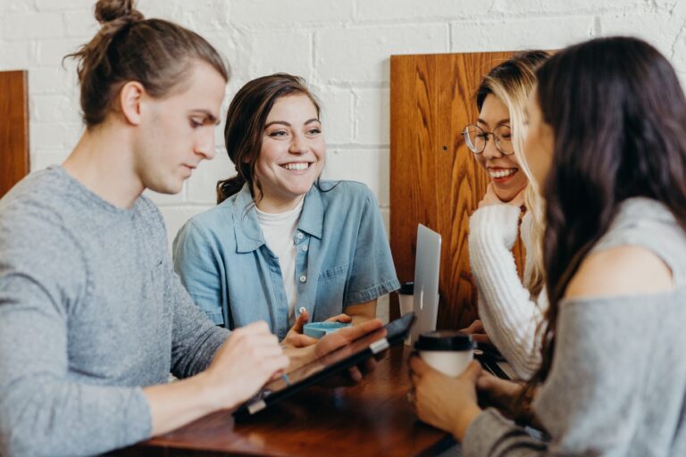 1 man and 3 girls gathered around a tablet laughing