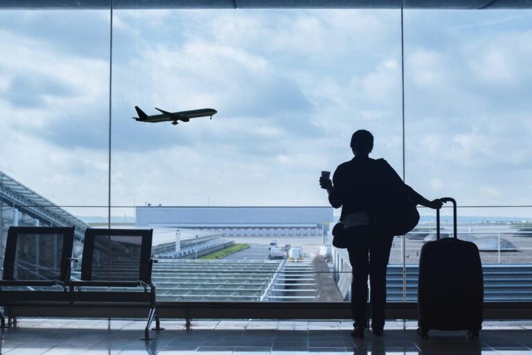 Traveller In Airport Looking At a Plane Taking Off