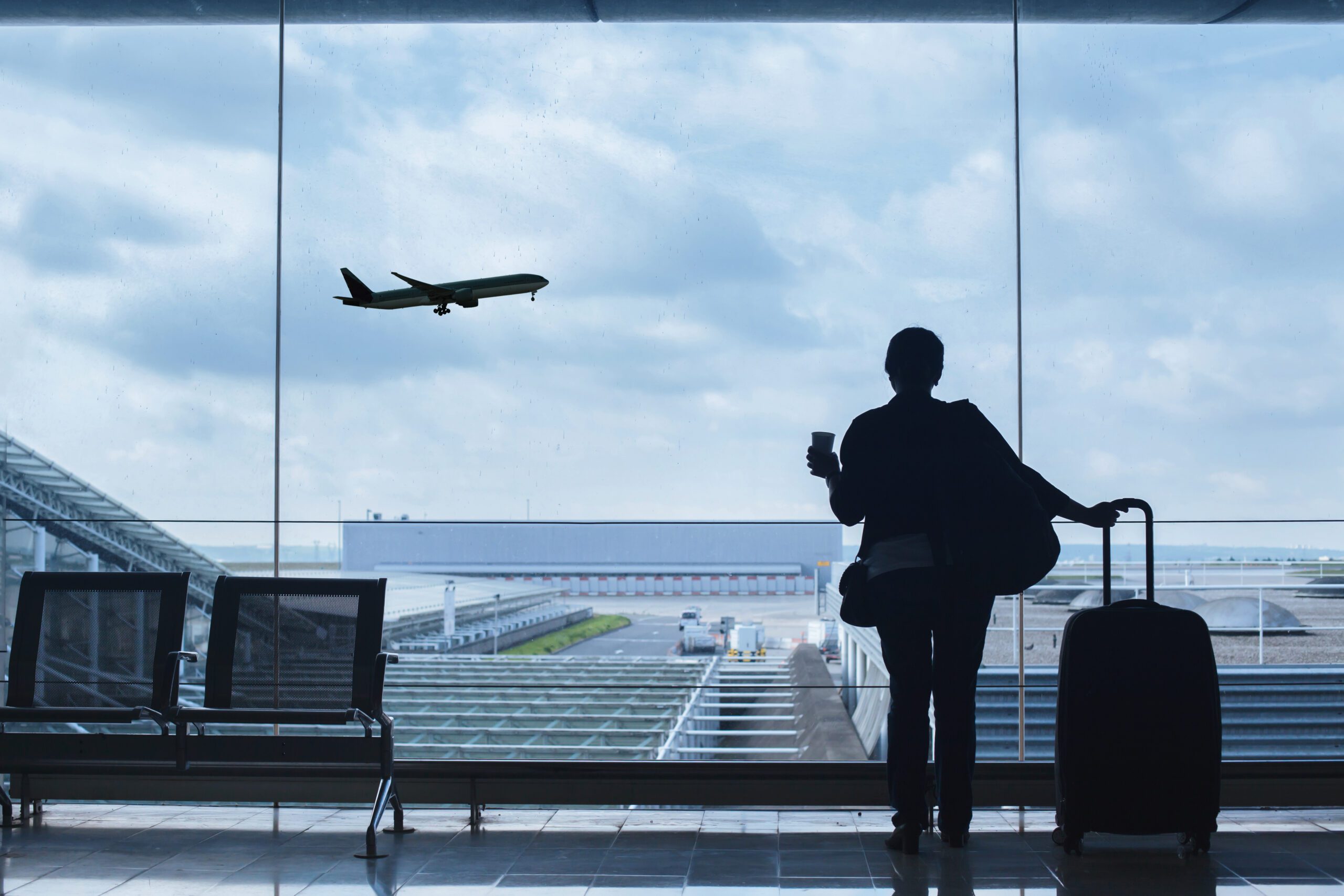 Traveller In Airport Looking At a Plane Taking Off