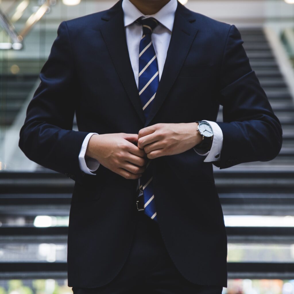 man wearing navy suit with blue striped tie