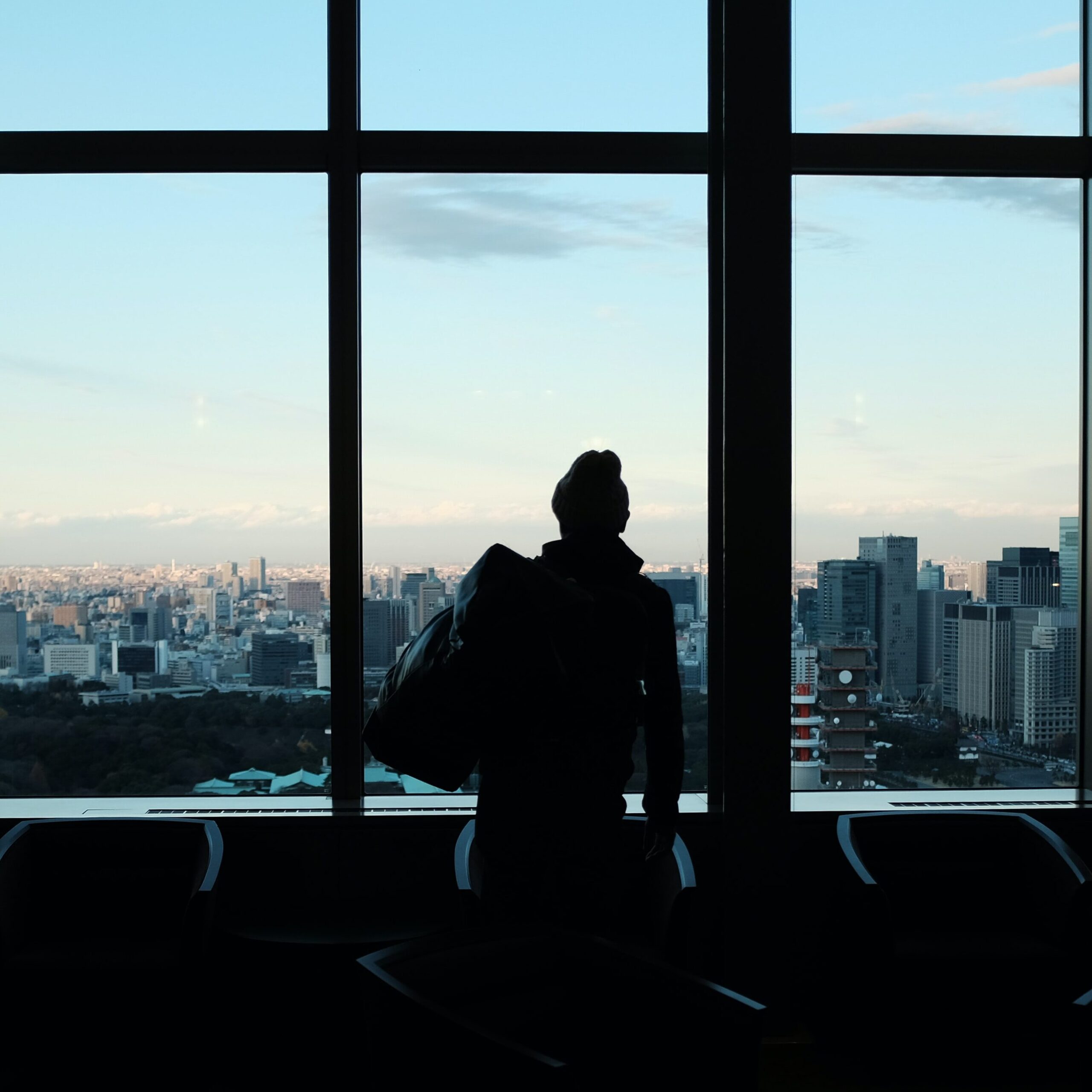 woman looking out window onto city