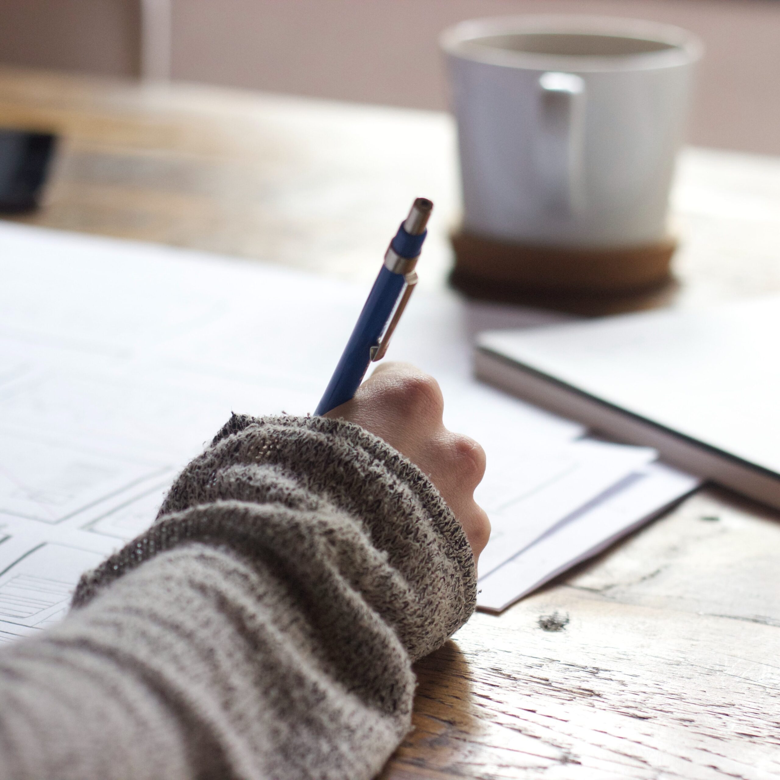 womans hand writing on paper with a pen