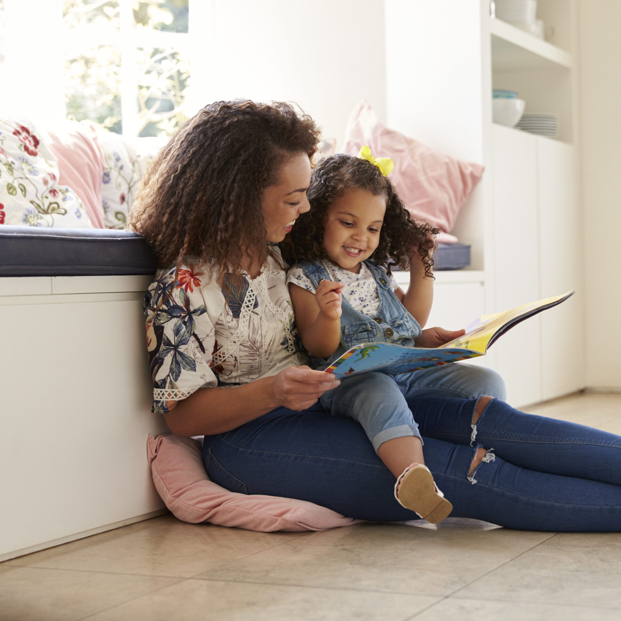 Mother,Sitting,On,The,Floor,Reading,A,Book,With,Her
